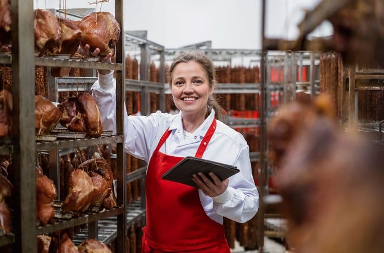 Femme en tablier dans un atelier de transformation de la viande.